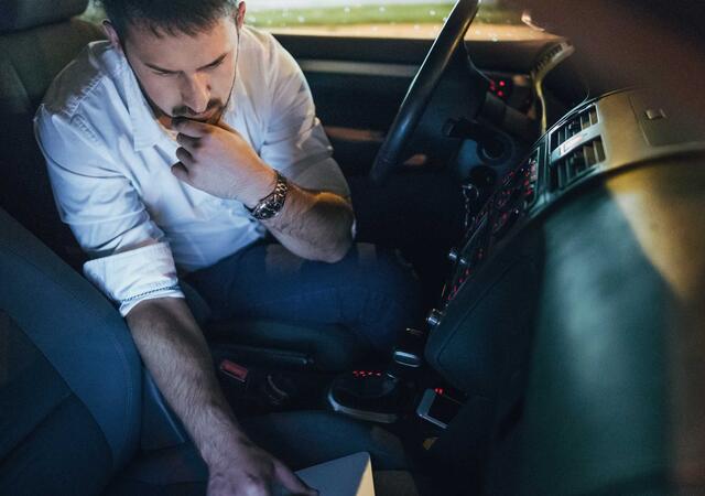 Man using laptop in a car