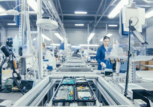Shot of an Electronics Factory Workers Assembling Circuit Boards by Hand While it Stands on the Assembly Line. High Tech Factory Facility.