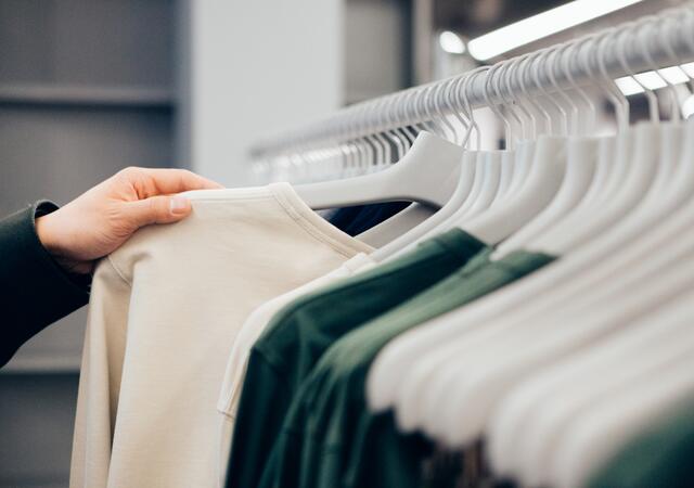 Cropped hand of man holding shirt in shop.