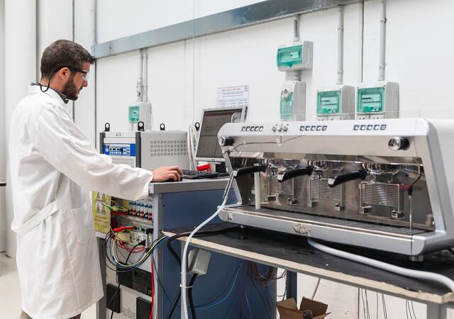 Laboratory technician conducting test on espresso machine.