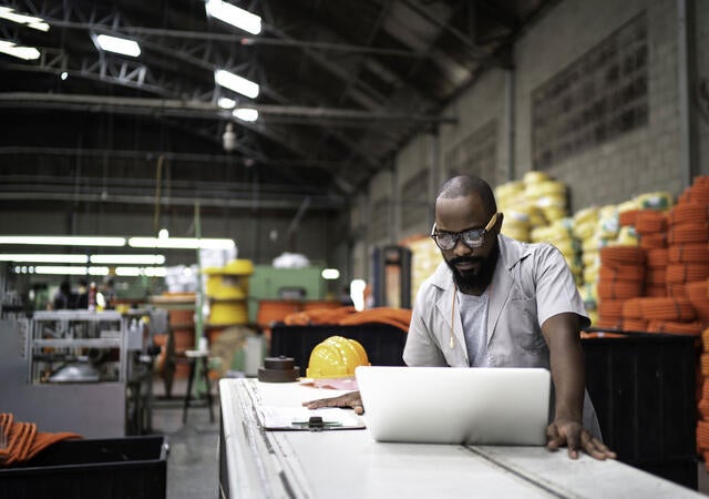 Person working on a laptop in a warehouse