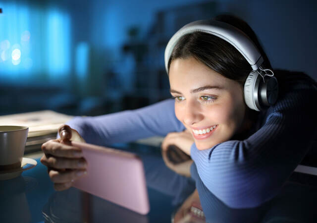 Woman wearing headphones and watching media on mobile phone