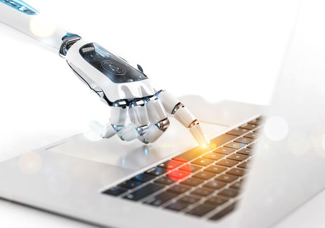 robotic arm typing on a laptop