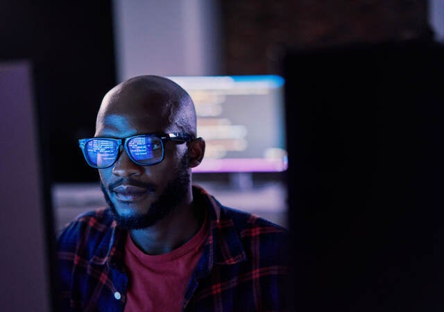It specialist in glasses reviewing work on a monitor