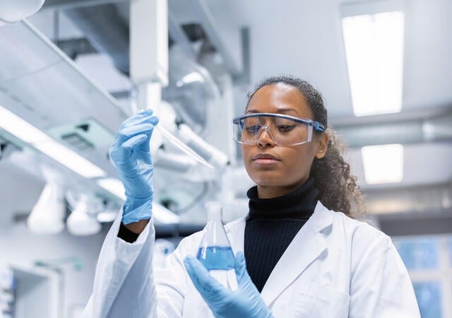 Chemist adding a sample to a solution in conical flask