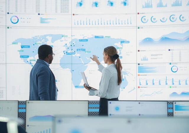 Two analysts looking at metrics on a digital map