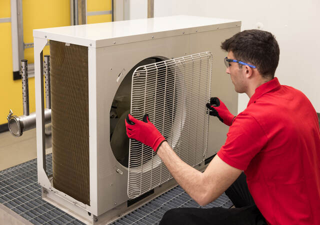 A person removing the grill of an HVAC unit