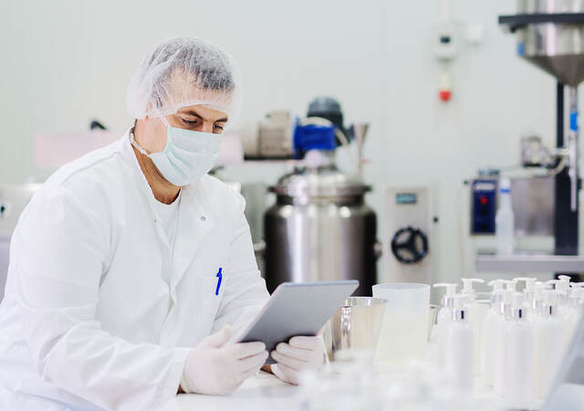 Scientist looking at a tablet while sitting in the lab in front of samples