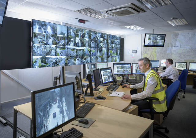 A security guard watching several monitors