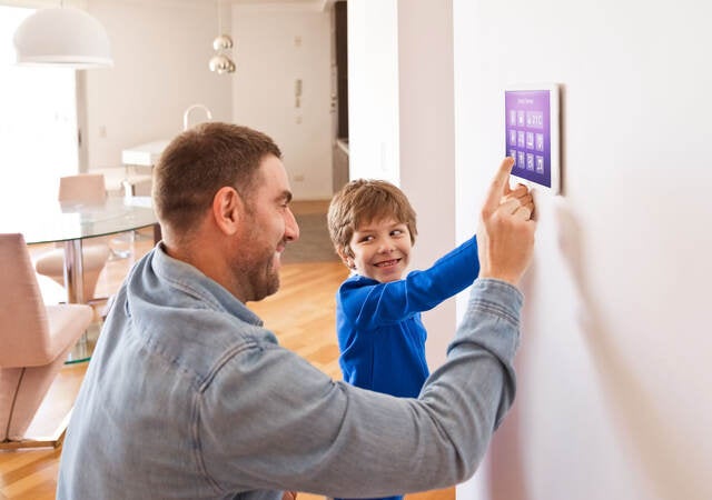 Father with son controlling smart devices with a digital tablet at home