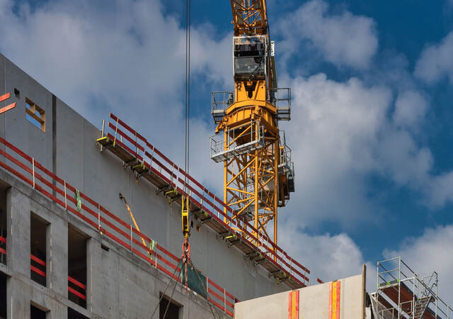 A crane on top of a building hoisting a heavy object
