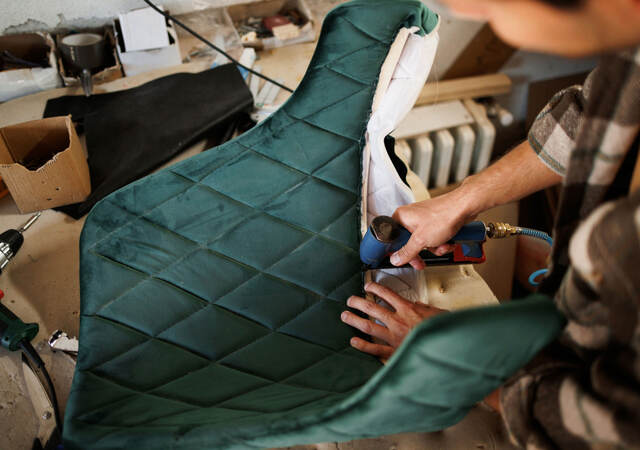 a person fixing the upholstery on a chair