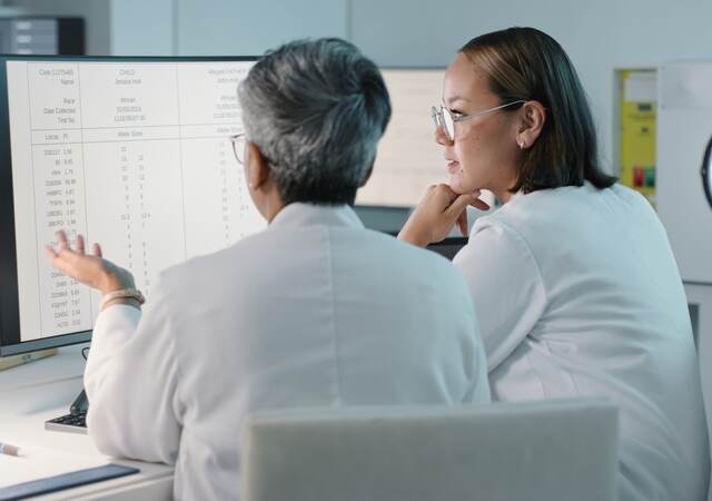 Two doctors look at a list on a computer monitor