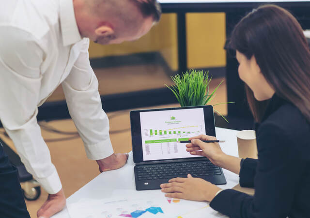Two people looking at data on a monitor