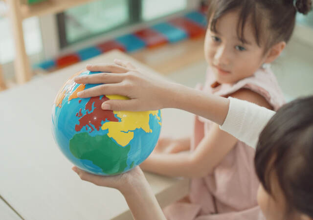 Kids playing with a toy earth globe