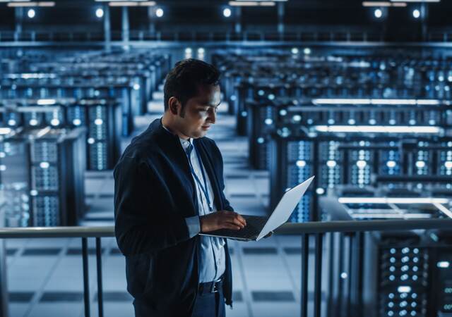 person on laptop in server room