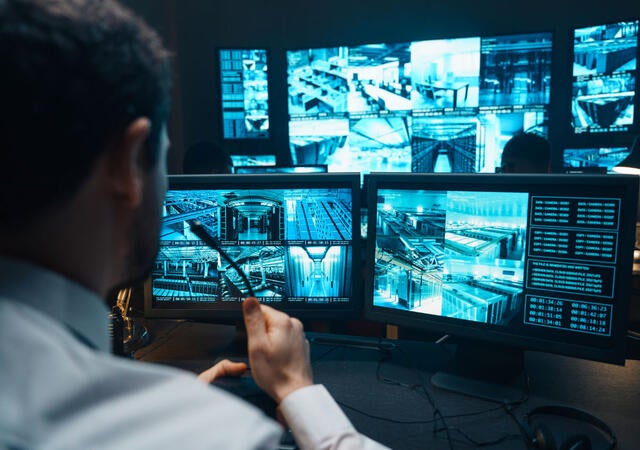 A person reviewing several security monitors