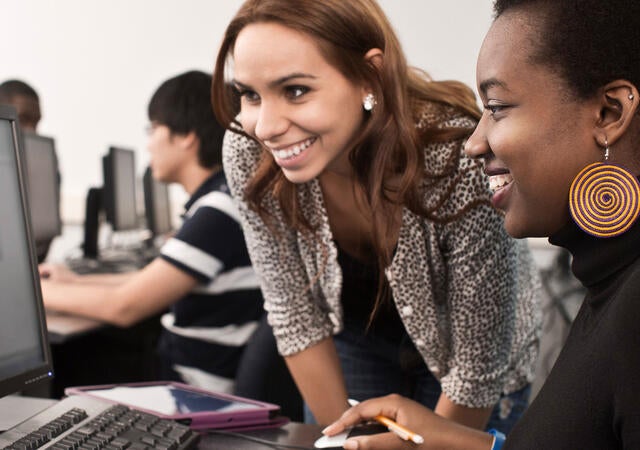 Two smiling people looking at a computer screen