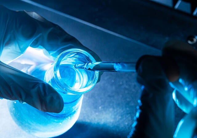 A lab technician pipetting liquid into a flask
