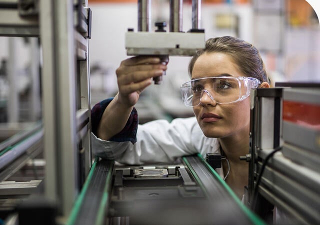 Quality control worker analyzing machine part on a manufacturing machine.