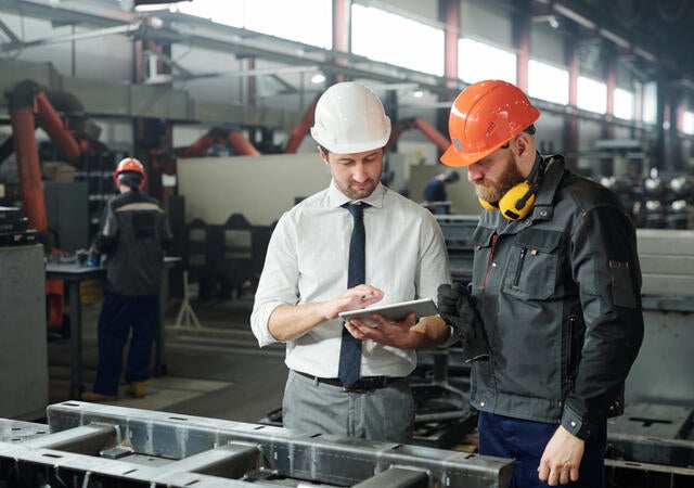 Manager and engineer looking at a tablet together on a factory floor