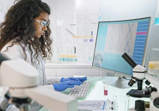 scientist in lab looking at DNA model on computer