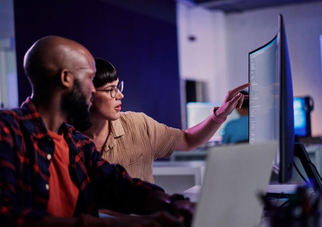 Two developers working together to review software code on a computer