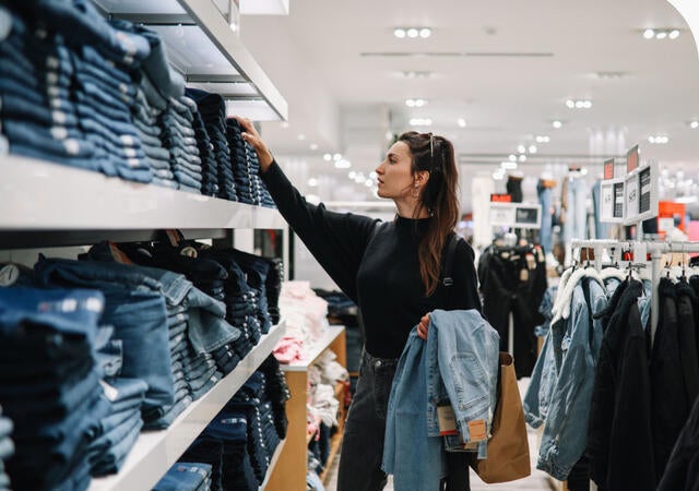 Person shopping for denim jeans in a clothing store