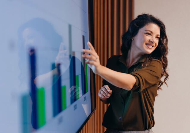 A business person presenting charts on a whiteboard
