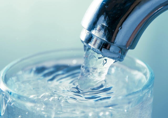 A glass being filled with water at a sink