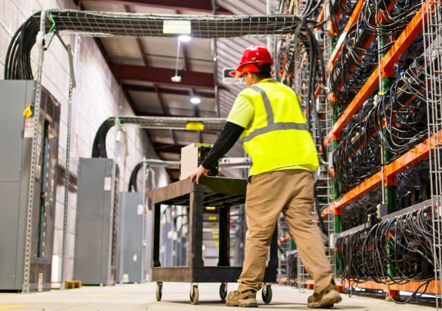 A technician pushing a cart in a massive data center