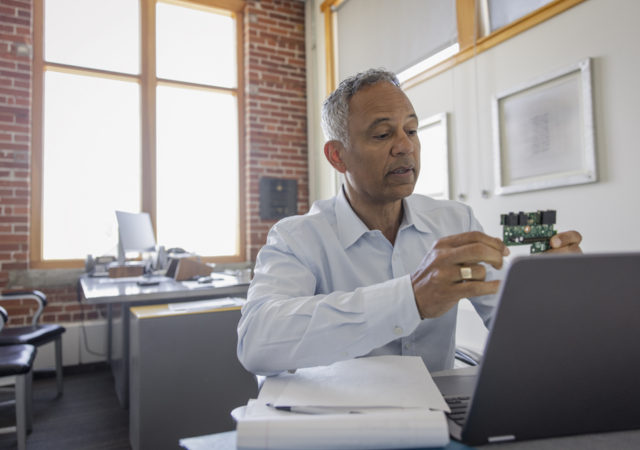 man inspecting circuit board in office