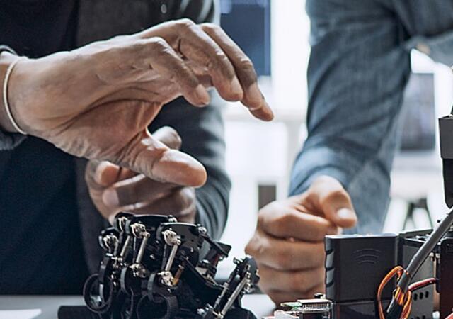 Two people assembling robotic hands in a lab.