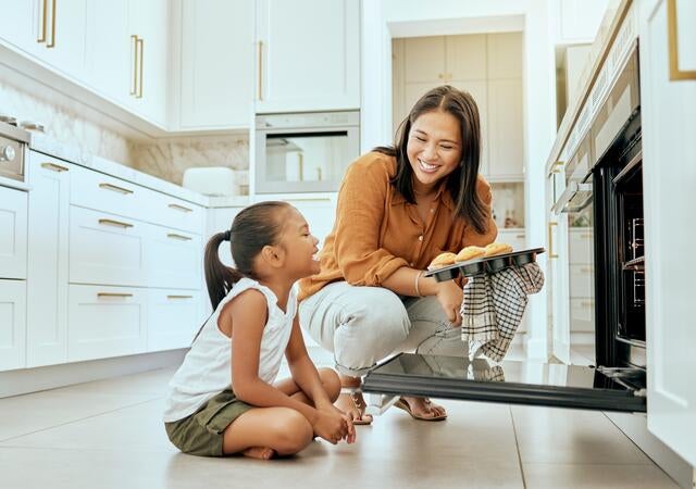 A parent and child looking at each other near an open oven