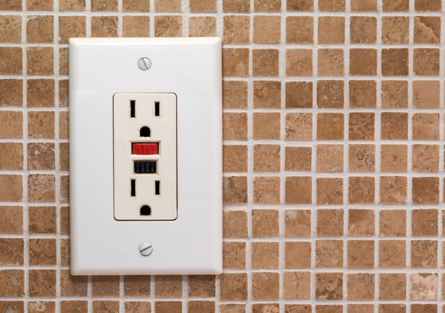 GFCI outlet installed on a tile wall background
