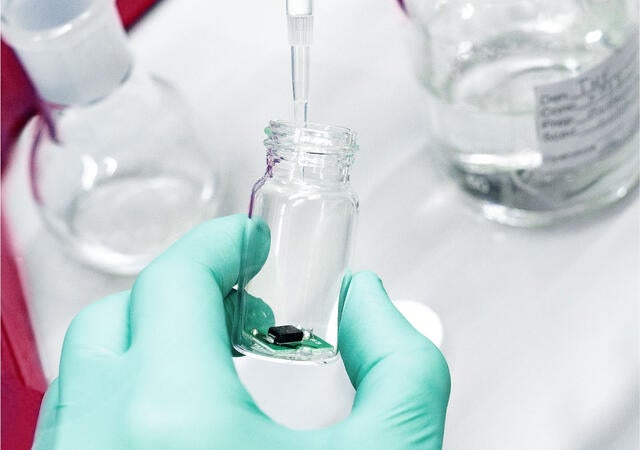 A laboratory technician using a pipette to drop liquid