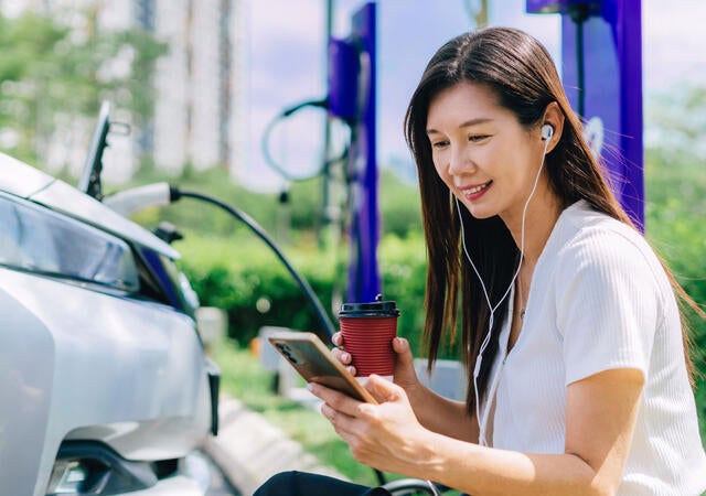 A person looking at a cellphone and wearing earbuds