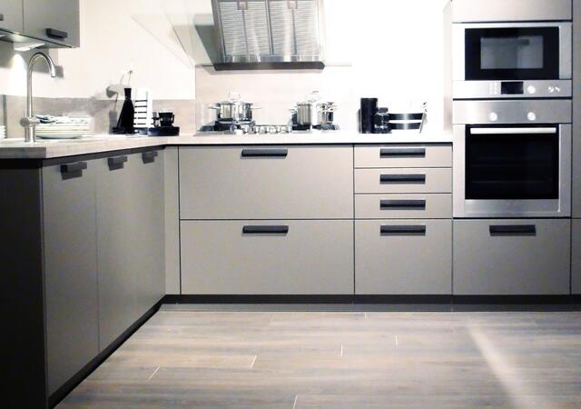 Modern kitchen with grey cabinets, stainless‑steel appliances, and a stovetop with pots.
