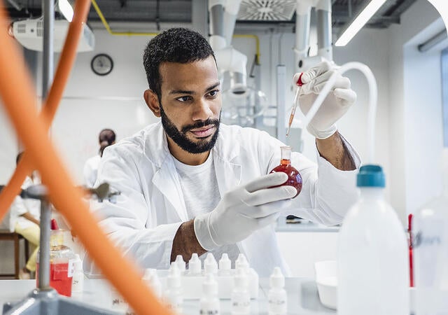 Scientist dropping a chemical into round bottom flask