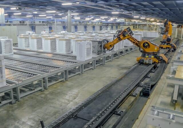 yellow robotic arms working on a production line assembling appliances