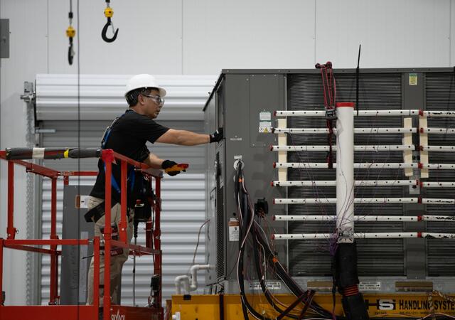 A person inspecting equipment at the Plano HVAC laboratory