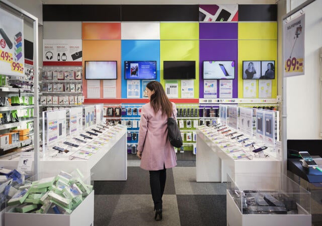 Shopper looking at mobile phones in an electronics aisle in a store
