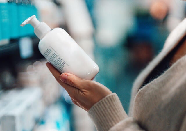 Person reading the label on a bottle of hand soap while shopping in a store