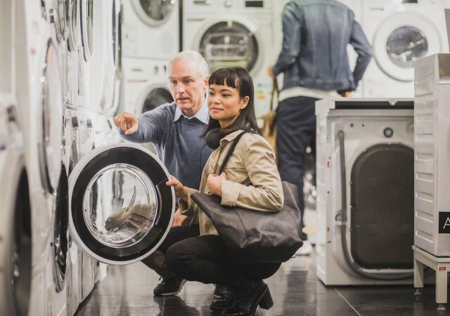 Two people examining a washing machine