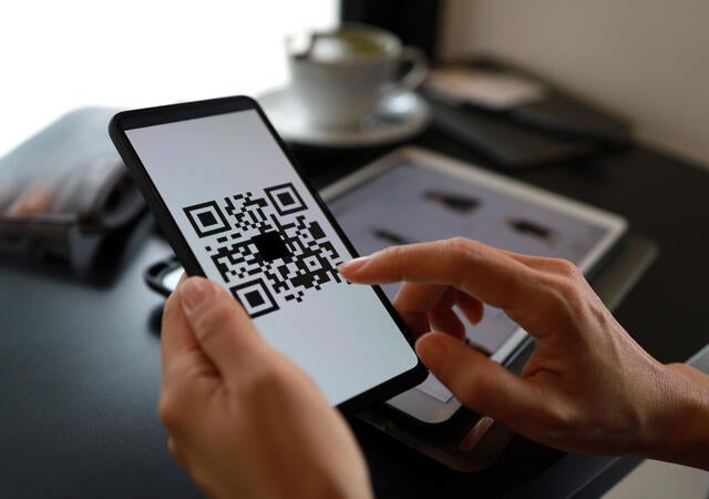 A person tapping on a QR code on a tablet screen
