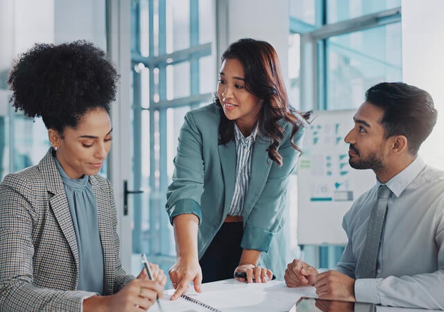 two women and man in business casual attire working at table in nicely lit office