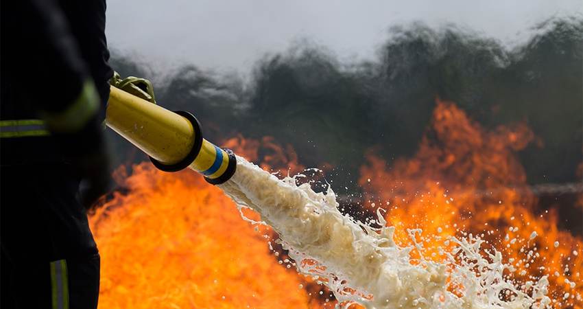 Firefighter spraying a fire with foam hose