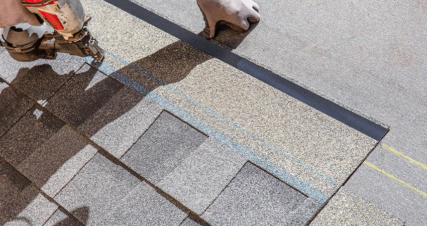 A worker nailing shingles on to a new roof.