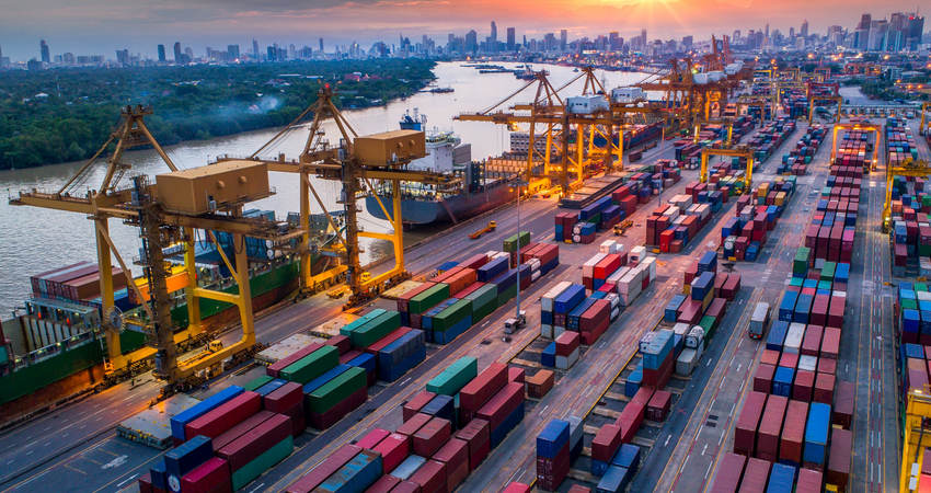 Container cargo ship and cargo plane with working crane bridge in shipyard at sunrise