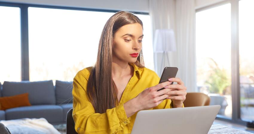 Woman using a smart phone and a laptop computer